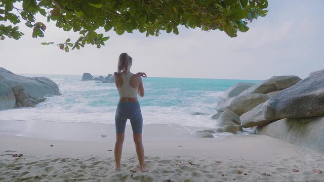 Sport concept. Woman stretching legs on beach in summer. Female athlete warming up before running.