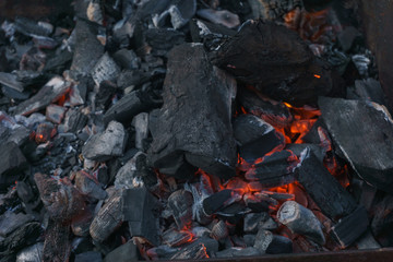 Hot coals and burning wood in the barbecue pit. Glowing and smoking charcoal, barbecue, red fire, and ash. Weekend.