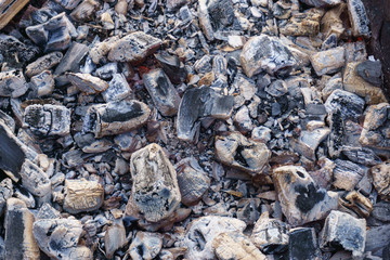 Hot coals and burning wood in the barbecue pit. Glowing and smoking charcoal, barbecue, red fire, and ash. Weekend.