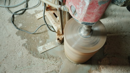 The builder drills holes in the concrete curtain for laying ventilation pipes and plumbing