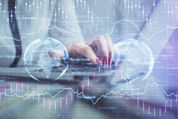 Double exposure of businesswoman hands typing on computer and financial graph hologram drawing. Stock market analysis concept.