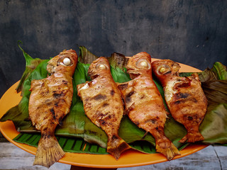four grilled fish covered with banana leaves