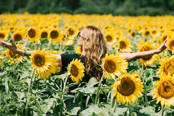 woman with open arms in a sunflowers field.