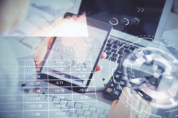 Double exposure of man's hands holding and using a digital device and forex graph drawing. Financial market concept.