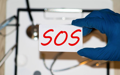 White lightbox with word SOS abbreviation of save our soul ship or sibling over shoulder on wood...