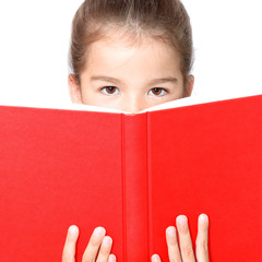 Young cute girl sitting at the table and reading a book