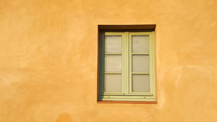 Sonnenbeschienene Hauswand, gelber Putz, Sprossenfenster
