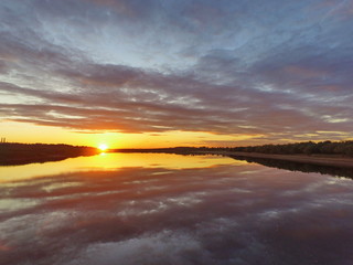 Fototapeta na wymiar Reflection of a fiery sunset in the water. Vychegda River, Komi Republic, Russia.