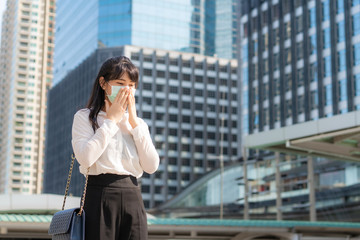 Young Asian businesswoman in white shirt going to work feeling sick with cough wears protection mask .