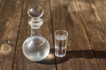 Vodka cold in a decanter and a stack lit by the bright sun