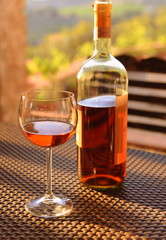 Weinglas und Flasche auf einer Terrasse im warmen Abendlicht der Toskana