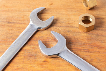 Two wrench and two copper nuts over the wood table