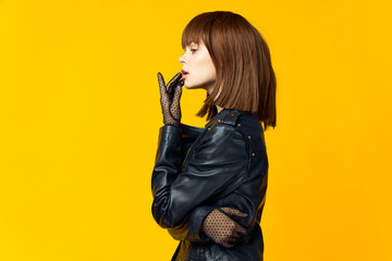 Woman on a bright yellow background in black clothes and gloves