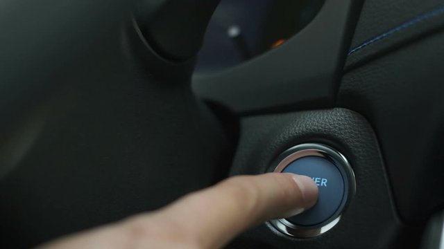 Finger Pushing blue button on  hybrid car engine key less ignition power, to start drive Closeup slow