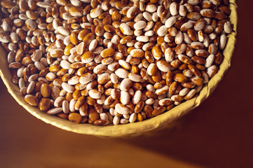 Exotic colorful mexican beans on wicker basket. Top view of legumes. Concept of beans food. Exotic beans on wooden table. Rustic background of beans. Colorful legumes on rustic setting.