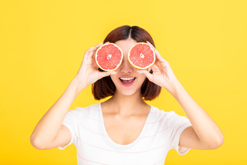 Young beautiful woman showing orange on yellow background