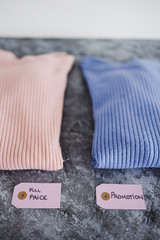 shopping concept, knit jumpers in alternative colours with Full Price vs Promotion price tags