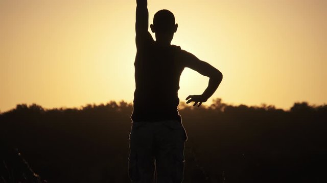 Silhouette of Man against Sunset Raising Hands Up. Freedom. Slow Motion
