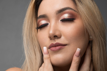 face of young blond Latina, white skin woman with makeup and long nails