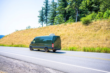 Fototapeta na wymiar Compact cargo dark gray mini van running for delivery on the winding summery road