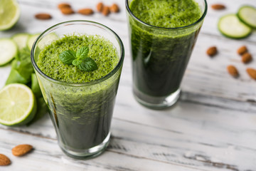 Spinach and almond smoothies against white wooden background. Concept of healthy food, eating, and lifestyle.