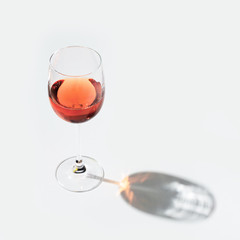 One glass of rose wine on light background with hard shadow
