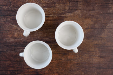Three white bowls, with handles, on a wood background
