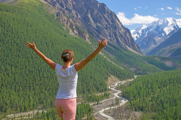 Fototapeta na wymiar Landscape girl in the mountains looks away with raised hands 