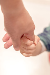 The boy's hand was held onto his father's finger while walking to stabilize him.