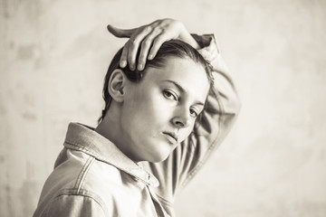 Tomboy straightens his hair. Tomboy in a denim jacket. Sepia portrait