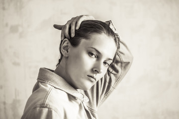 Tomboy straightens his hair. Tomboy in a denim jacket. Sepia portrait