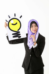 South East Asian young Malay woman wearing formal business office ware headscarf on white background holding idea light bulb sign