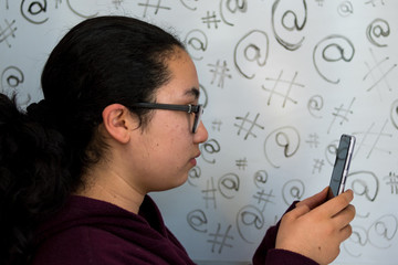 Girl watching the cellphone with some technology symbols as background 