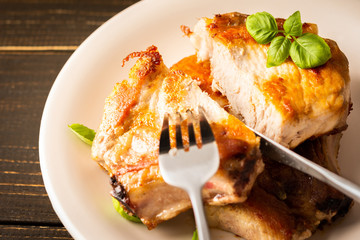 Fried pork entrecote on the bone, cooked pieces of pork meat with basil leaves and spices, cut steak on the bone in a plate on a wooden background