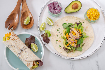 Fresh tortilla wraps with chicken, mushrooms and fresh vegetables on wooden board