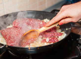 Woman chef frying minced meat in a pan