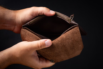 empty leather wallet in the hands of a man on a dark background. Financial crisis. close-up