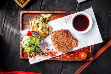 Fillet mignon steak on board with salad and sauce