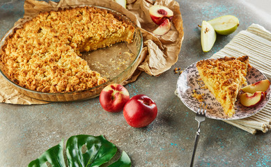 Homemade cakes, pie in a baking dish and a slice on a plate with peaches and pears on gray-blue concrete.