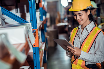 Engineer warehouse woman wearing a hardhat standing cargo at goods warehouse and check for control...