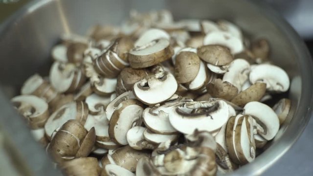 Sliced fresh champignon mushroom in enamelware bowl 
