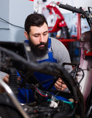Fototapeta na wymiar Young male worker repairing motorbike in motorcycle workshop