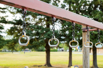 Playground in the park. Metal monkey bars on chains. Playground for children in the local park with field and trees in the background. 