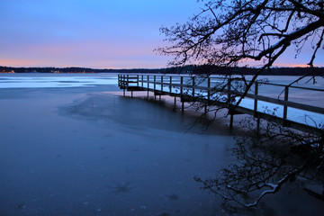 Snowy pier and frozen lake in Kaarina, Finland.