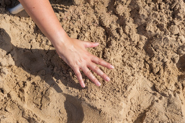 HAND OF A YOUNG GIRL WITH A BEACH SAND BACKGROUND