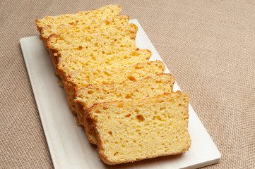 Homemade Brazilian corn bread sliced on a cutting board. Isolated on jute background