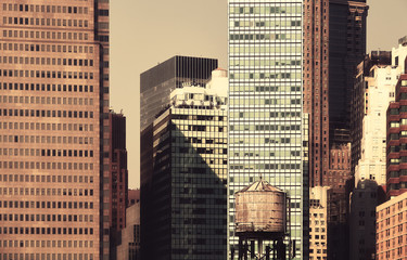 New York City diverse architecture with old wooden water tower in foreground, retro color toned picture, USA.