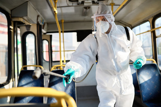 Sanitation worker disinfecting public bus in order to prevent the spread of COVID-19.