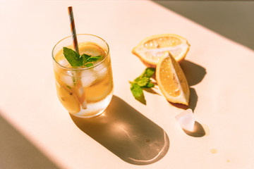 Fresh lemonade with mint leaves and ice cubes on yellow background, sharp shadows, top view
