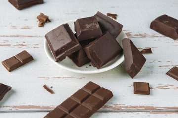 Pieces of chocolate with chocolate shavings on white Provence style table.